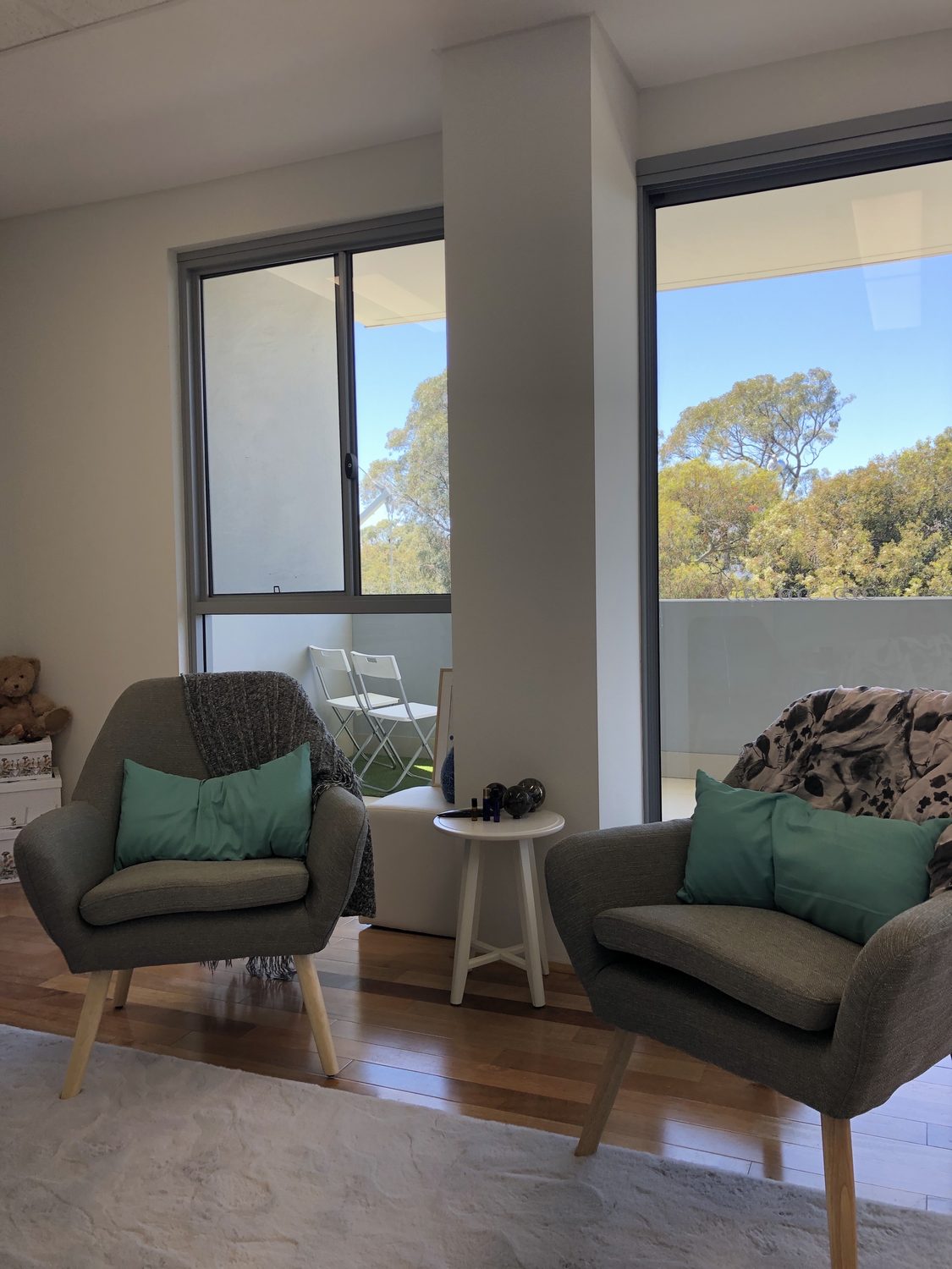 A therapy room at Green Road Psychology — two armchairs facing each other, with windows looking out over gum trees.